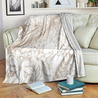Beige and white tropical floral print blanket, folded and covering a sofa