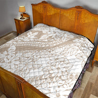 Beige and white floral print quilt with diamond stitching, black edge trim on bed.