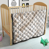 Beige and white floral quilt for crib with diamond quilting and black border trim.