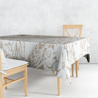 Beige and white tablecloth with geometric leaf and scroll print, draped over table