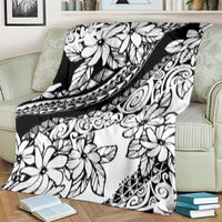 White and black floral blanket with geometric tribal bands, draped on a couch