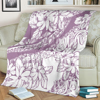 Purple and white Polynesian floral blanket folded on an armchair