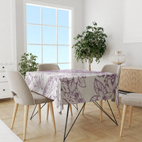 Purple and white floral tablecloth covering a dining table in a room setting.