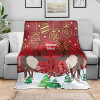 Red and white Christmas blanket draped on a sofa, featuring caribou and pine trees