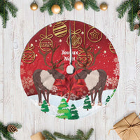 Red Christmas tree skirt with reindeer and Joyeux Noel text, round white fringe edge