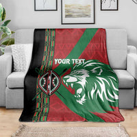 Custom blanket folded over sofa: red, green, and black tribal pattern with lion artwork
