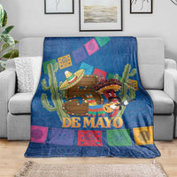 Blue throw blanket with 'DE MAYO' lettering, cactus, and festive illustrated figures