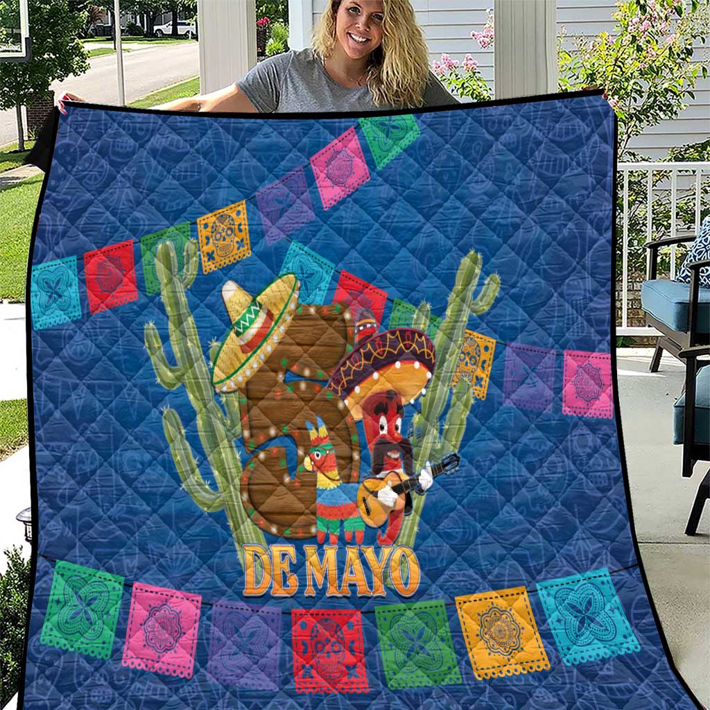 Blue quilt close-up with cactus fiesta figures, “DE MAYO” lettering, and multicolor squares.