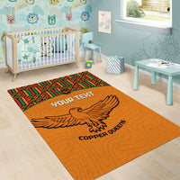 Orange area rug with Kente border and eagle, showing 'YOUR TEXT' and 'COPPER QUEENS'