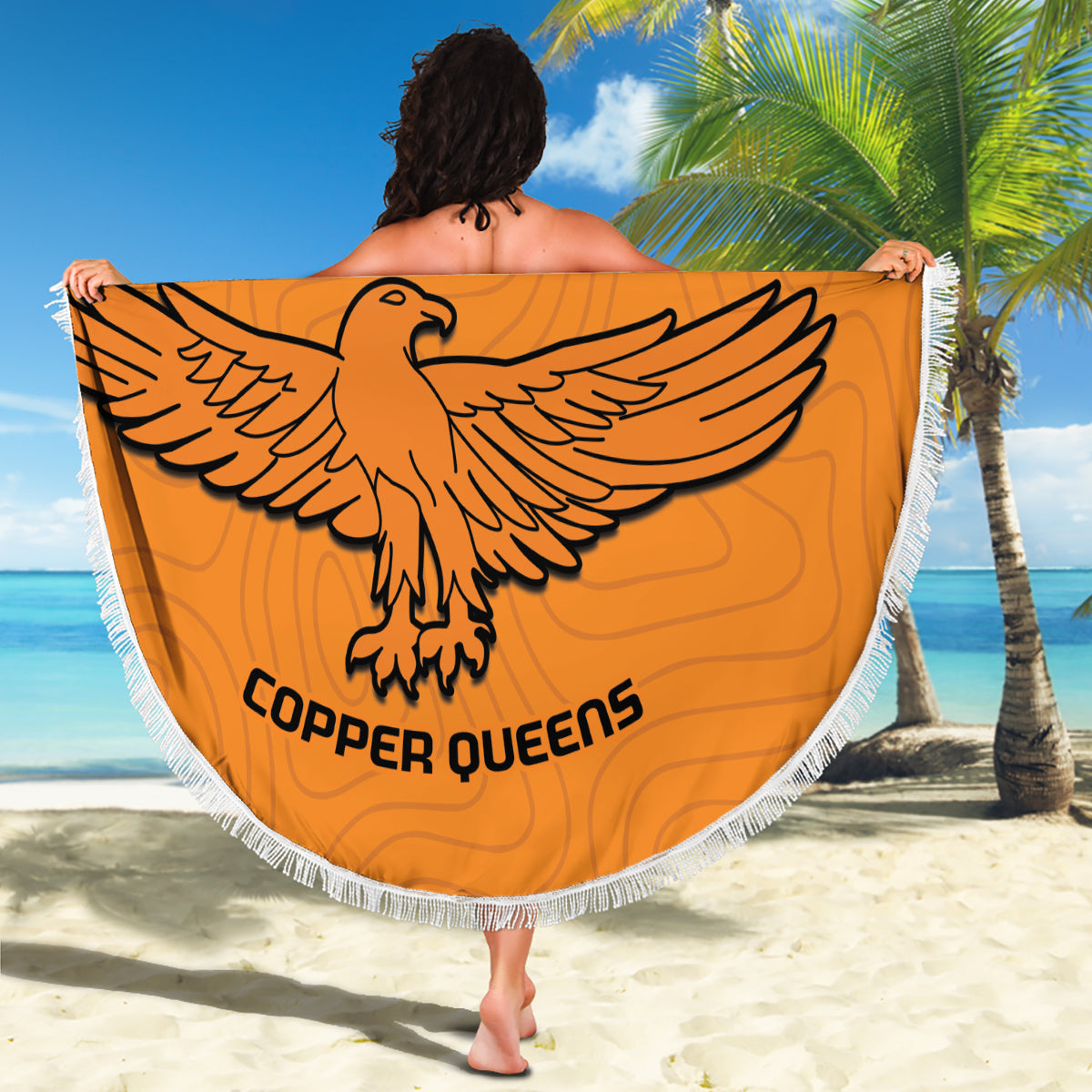 Orange round beach blanket with white fringe, eagle emblem and 'COPPER QUEENS' text