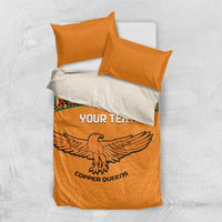 Orange duvet with Kente-striped panel and bird emblem, paired with two orange pillows