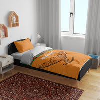 Orange duvet and two pillows with Kente stripes and bird emblem print across the center