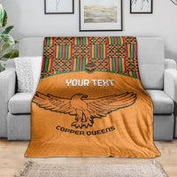 Orange football blanket on gray sofa with Kente top trim, eagle graphic, and Custom text