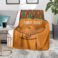 Orange football blanket draped on floor with Kente top trim and eagle graphic