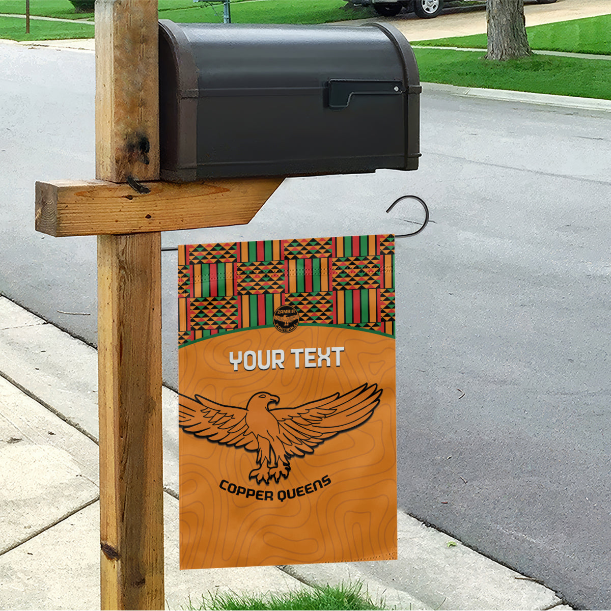 Orange house garden flag with Kente-style top border, eagle emblem, and Copper Queens logo