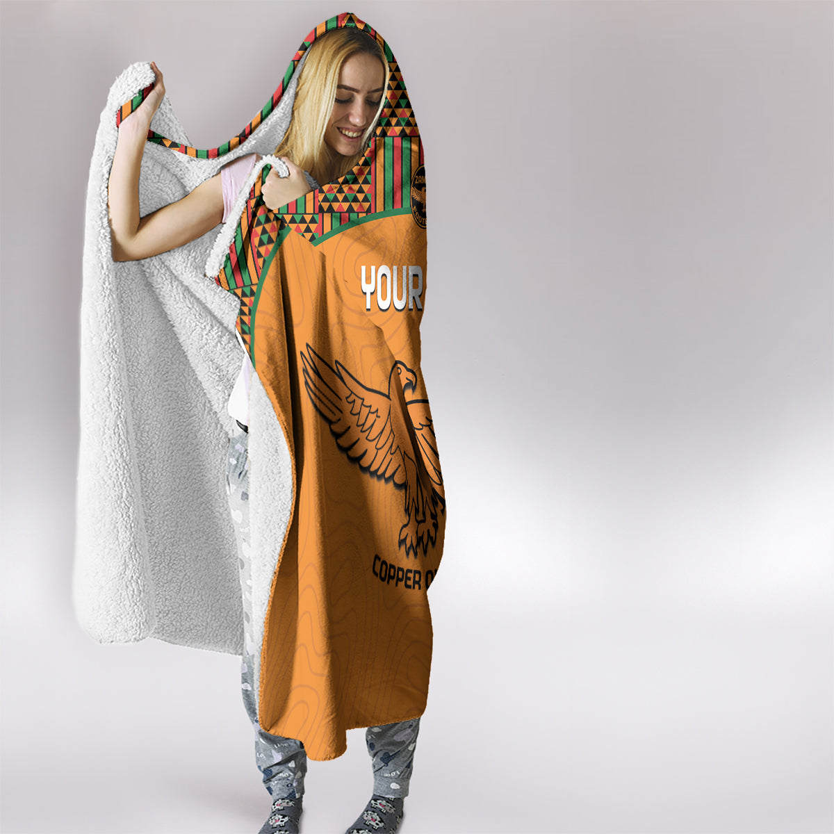 Orange hooded blanket with Kente trim and “YOUR TEXT” graphic, eagle emblem on back