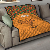 Orange quilted blanket with multicolor Kente border and eagle graphic on sofa