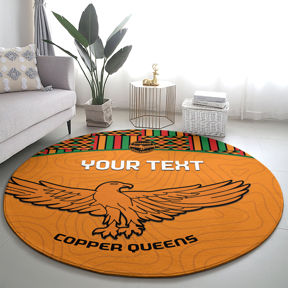 Orange round football rug with kente trim, eagle emblem, and 'COPPER QUEENS' lettering