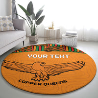 Orange round football rug with kente trim, eagle emblem, and 'COPPER QUEENS' lettering
