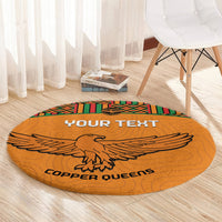 Orange round rug with 'YOUR TEXT' and eagle graphic, finished with kente striped edge