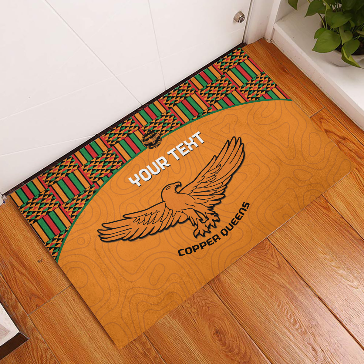 Orange rubber doormat with green and red kente border and eagle emblem
