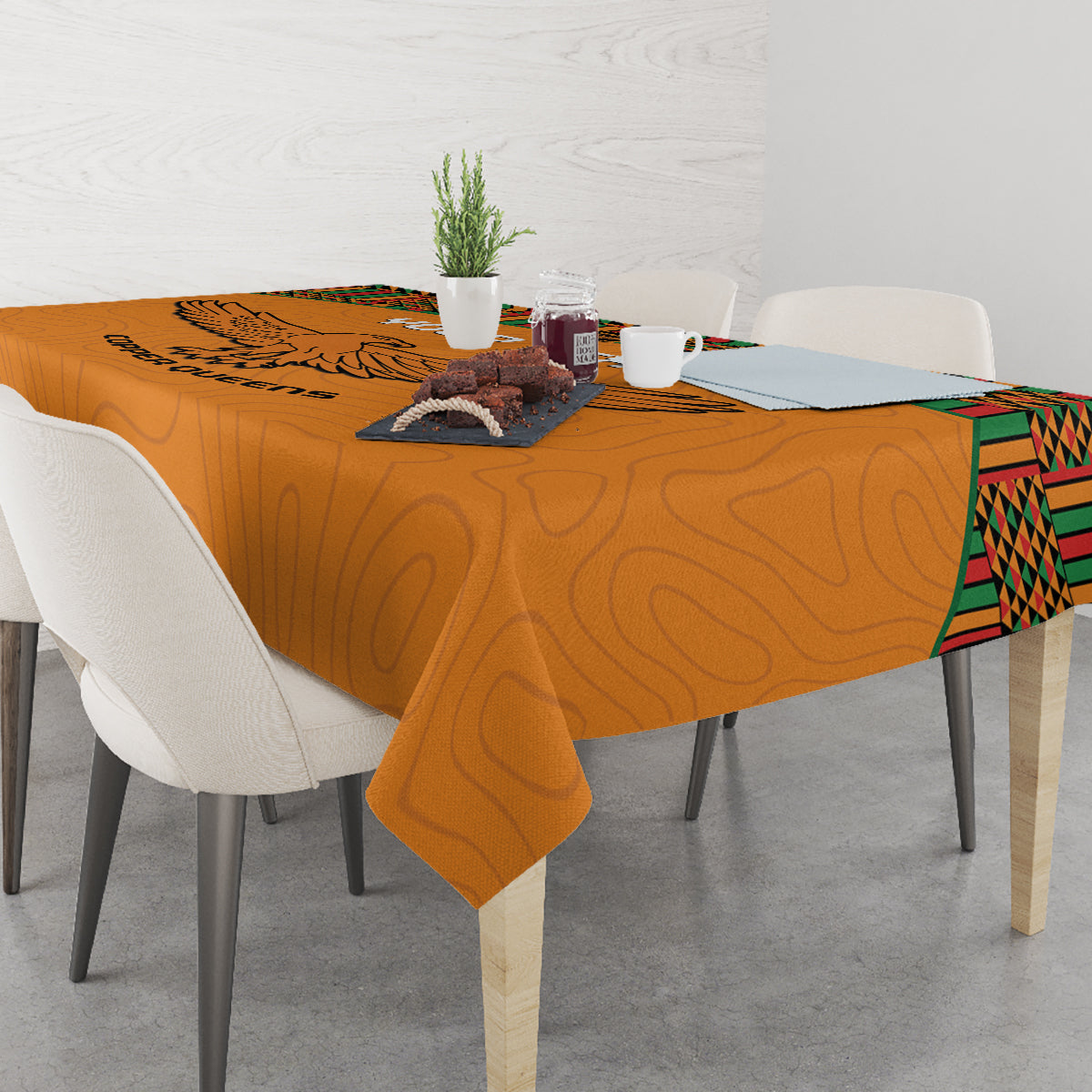 Orange football tablecloth with eagle print and kente border, draped over dining table