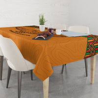 Orange football tablecloth with eagle print and kente border, draped over dining table