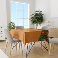 Orange football tablecloth with kente border and eagle design on long dining table