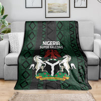 Green and black Super Falcons football blanket draped over couch with team crest