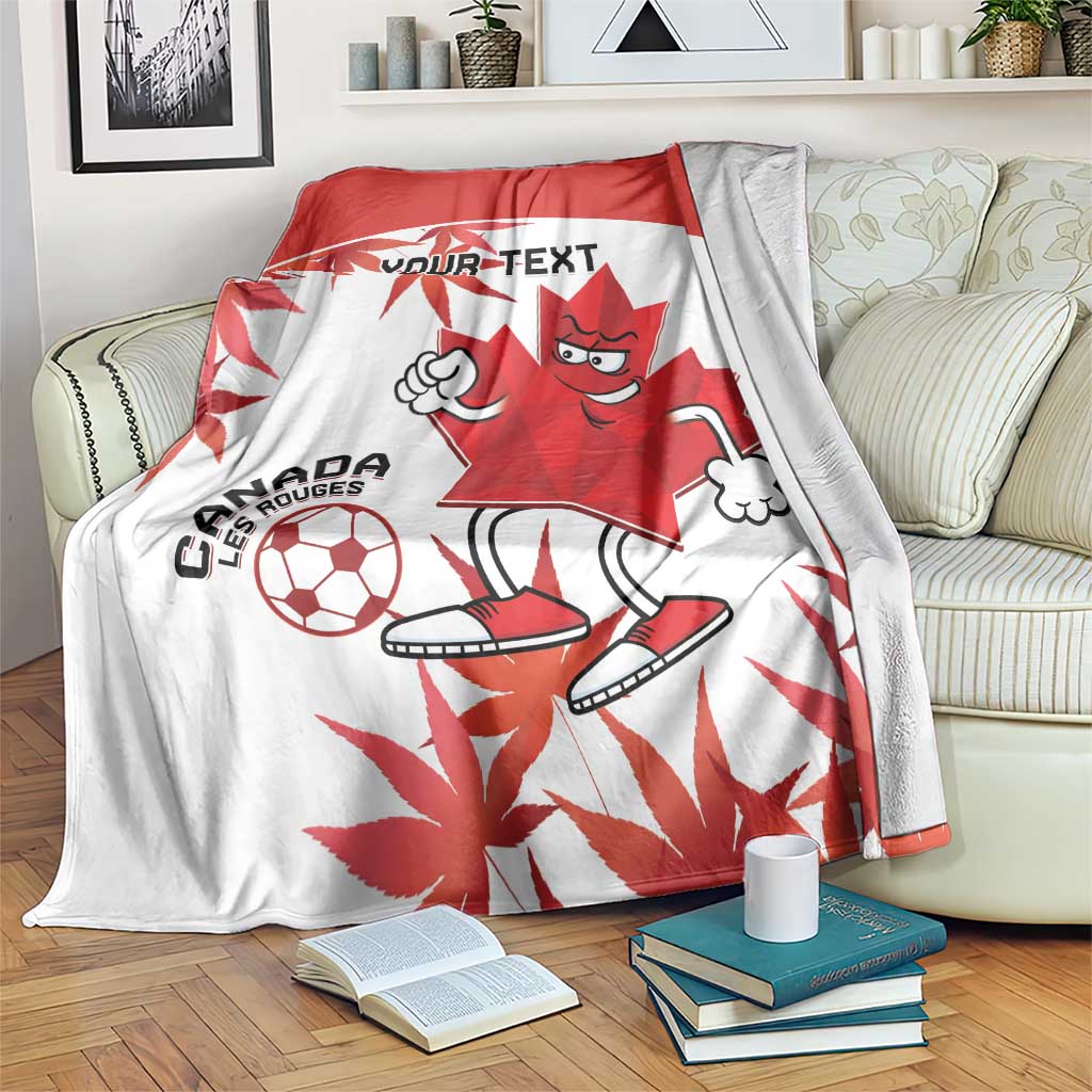 Canada soccer blanket draped on couch, red-and-white mascot with maple leaf and soccer ball