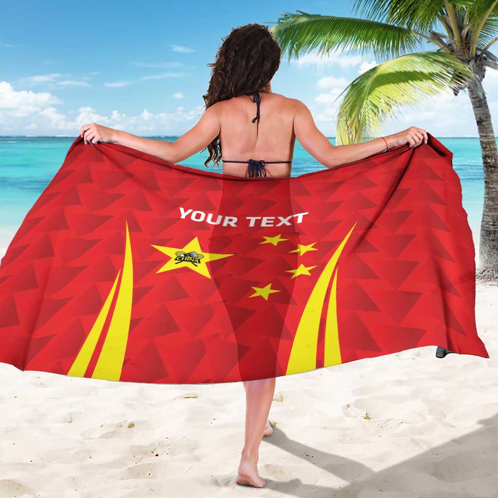 Red personalized sarong with geometric flag pattern, stars, and bold center text