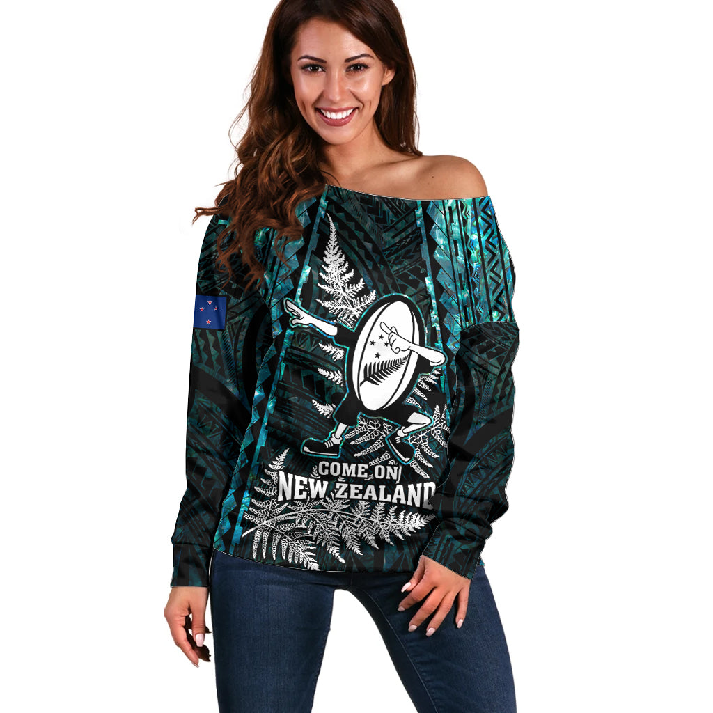 Women’s off-shoulder rugby sweater in turquoise and dark green, front graphic and lettering