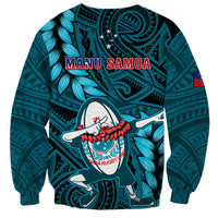 Turquoise rugby sweatshirt with Manu Samoa text, dabbing player graphic, leaf patterns