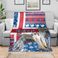 Blue Christmas blanket draped over sofa, with gyrfalcon, snowflakes, and Nordic design