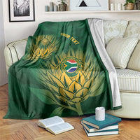 Green cricket blanket with gold crest, tropical leaves, and custom text, draped on a sofa