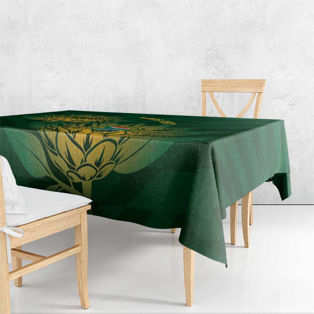 Green tablecloth with gold crest medallion and leaf artwork, hanging over a wooden bench.