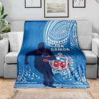 Blue fleece rugby blanket draped on a sofa, featuring a Polynesian shield and player