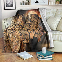 Black Aztec-themed blanket with golden warrior and hummingbird graphic, draped on couch