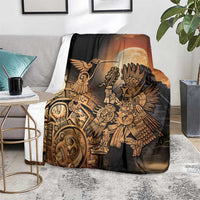 Black Aztec blanket with gold hummingbird and warrior, spread on floor beside table