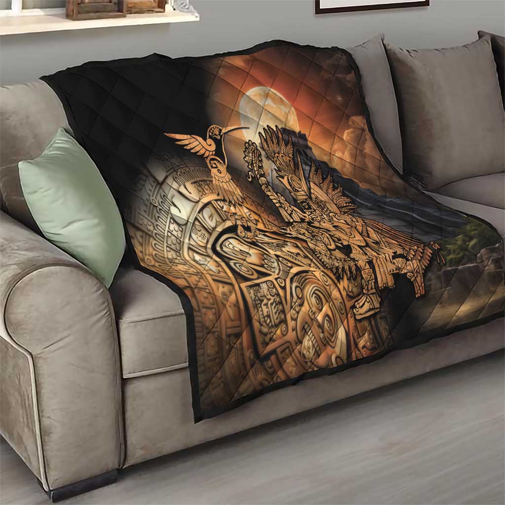 Black quilted throw blanket on sofa with Aztec warrior and feathered bird design in gold