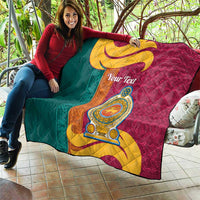 Teal and maroon quilt draped outdoors with gold crest emblem and swirling scroll, quilted.