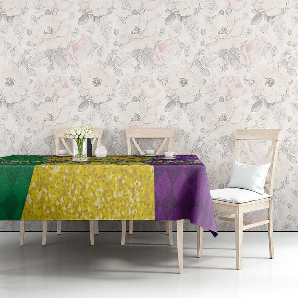 Mardi Gras tablecloth spread on table in purple, gold, and green with fleur-de-lis details