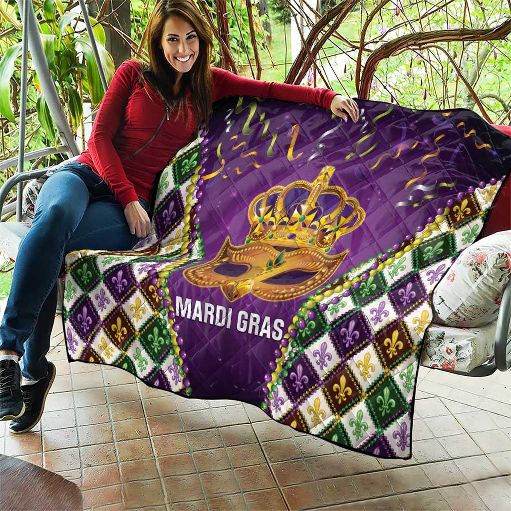 Purple quilt held outdoors with gold crown mask and 'MARDI GRAS' text, fleur-de-lis border
