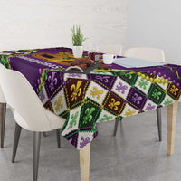 Purple tablecloth with green, yellow, and gold diamond pattern and fleur-de-lis accents
