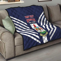Navy quilt with white diagonal stripes and Bermuda crest, draped on a sofa.