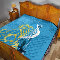 Blue quilt laid over bed with Saint Lucia Kings gold lion, oval design, diamond stitching