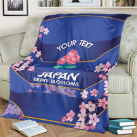 Blue rugby blanket on sofa with 'JAPAN BRAVE BLOSSOMS' text and pink cherry blossoms