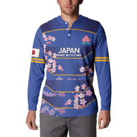 Blue rugby button sweatshirt on model with cherry blossom logo and yellow-striped design