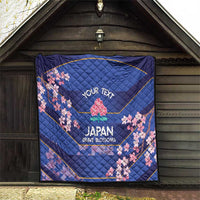 Blue quilt hanging indoors with pink cherry blossoms and 'JAPAN BRAVE BLOSSOMS' wording