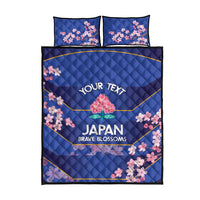 Blue quilt bed set with pink cherry blossom pillows and “JAPAN BRAVE BLOSSOMS” text